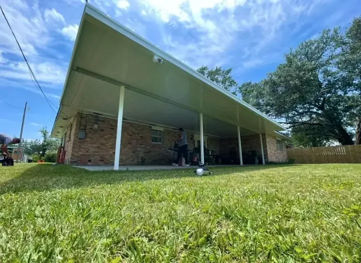 A long aluminium patio cover running the length of a lawn beside a brick home
