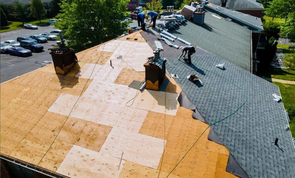 A crew mid-install on a roof deck with chimneys visible