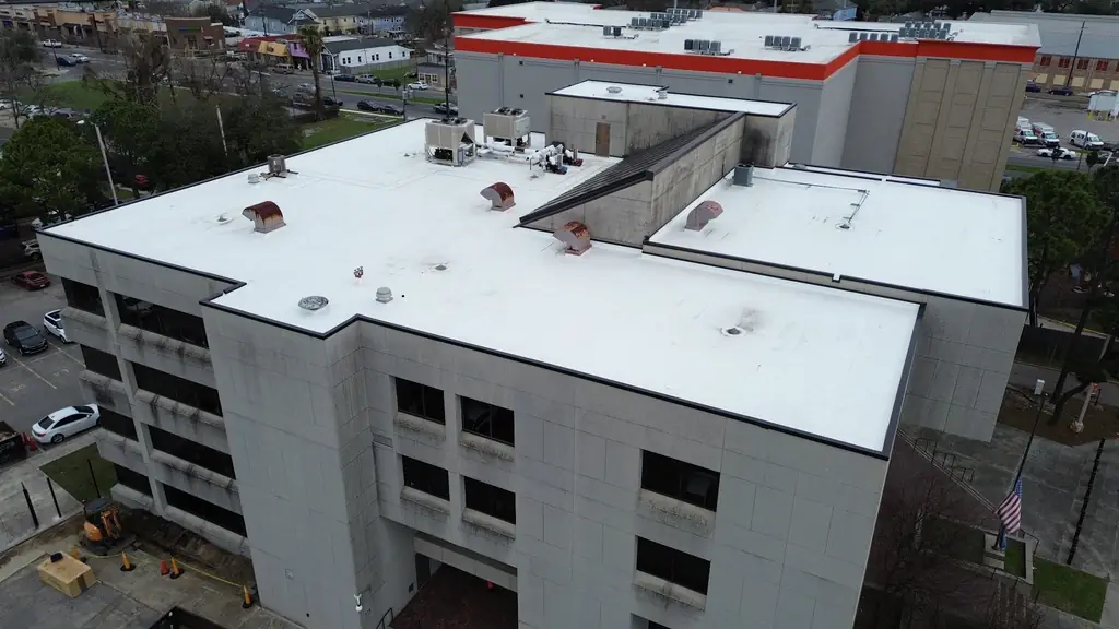 Aerial view of a completed white TPO roof on a multi-storey building beside a parking deck