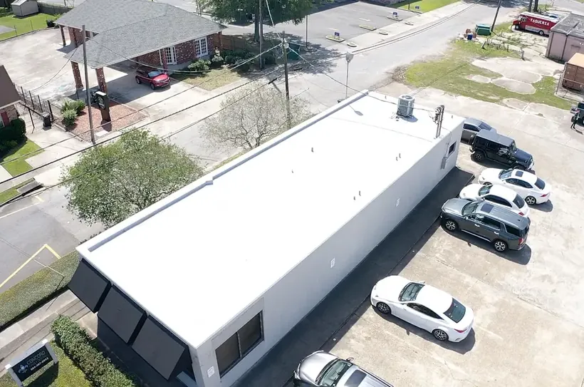 Aerial view of a completed white flat roof on a long commercial building